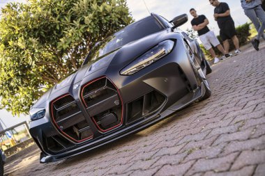 Roma, İtalya, 18 Temmuz 2025, özelleştirilmiş BMW arabası ızgarada benzersiz kırmızı aksanlar var, tuğladan yapılmış bir yüzeye park edilmiş.