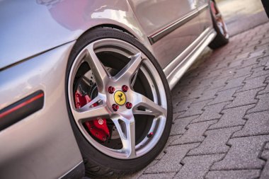 Roma, İtalya 18 Temmuz 2025. Alaşımlı tekerleğini, kırmızı fren kalibresini ve tekerlek fındıklı ferrari logosunu vurgulayan gümüş bir spor arabaya yaklaş.