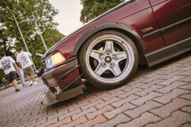 Roma, İtalya, 18 Temmuz 2025. Özelleştirilmiş bmw e36 piyasa sonrası vücut kitinin düşük açılı görüntüsü. Parçalanma ve çamurluk fişekleri ve tuğladan yapılmış bir yüzeye park edilmiş eşsiz tekerlekler de dahil.