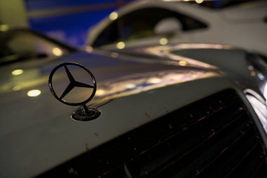 Roma, İtalya 18 Temmuz 2025, Mercedes Benz logosunu bir araba kaputuna kapatın, park yerindeki ışıkları yansıtın, lüks ve otomotiv tasarımı sergileyin.