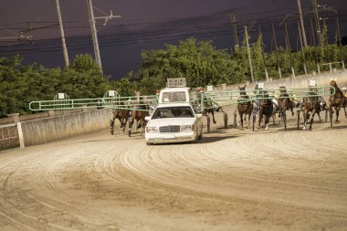 Padua, İtalya. 18 Temmuz 2025. Önde gelen bir araba tarafından çekilen atlar gece bir pistte koşuyor.