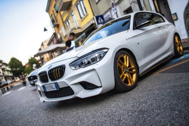 Roma, İtalya 5 Ağustos 2025: özelleştirilmiş beyaz bmw serisi 1 şehir caddesinde park edilmiş altın jantlar