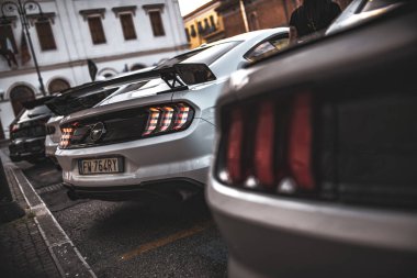 Roma, İtalya 5 Ağustos 2025: Beyaz Ford Mustang 'in dikiz manzarası ve diğer benzer arabaların yakınındaki bir şehir caddesinde park edilmiş farları.