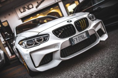 Roma, İtalya 5 Ağustos 2025: Lüks bir butiğin yakınına park edilmiş modern beyaz spor yara izi güçlü ön tasarımını sergiliyor.