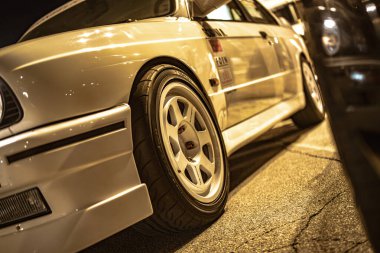 Roma, İtalya 5 Ağustos 2025: Akortlu beyaz bmw e30 m3 'ün düşük açılı görüntüsü geceleyin asfalta park edilmiş