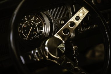 Klasik bir gösterge paneline yakın plan hız göstergesi, yakıt göstergesi, ve özgün bir direksiyon, nostalji ve otomotiv tarihini çağrıştırıyor.