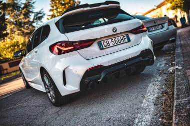 Calaone, İtalya 13 Ağustos 2025, park halindeki beyaz BMW 1 serisi, ikamet edilen bir sokakta arka lambalarını gösteriyor.