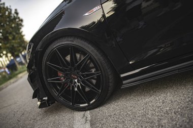 Calaone, İtalya 13 Ağustos 2025: özelleştirilmiş siyah bir Volkswagen golf gti 'sinin yakın çekimi, ön tekerleği, alaşım jantları ve kırmızı fren kalibreleri vurgulanıyor.