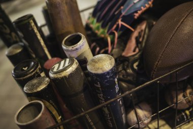 Calaone, İtalya 13 Ağustos 2025: Beyzbol sopaları, eldivenler ve futbol topları gibi çeşitli spor malzemeleriyle dolu metal sepet aktif bir yaşam tarzını somutlaştırıyor.