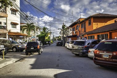 Bayahibe, Dominik Cumhuriyeti 19 Ağustos 2025: Dominik Cumhuriyeti 'nin turistik bir kasabası olan Bayahibe caddesi boyunca güneşli ve bulutlu bir günde park etmiş arabalar