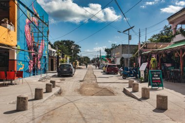 Tulum, Meksika 20 Ağustos 2025: Tulum Pueblo, Meksika sokak manzarası, güneşli bir günde arabaları, binaları, duvar resimlerini, elektrik hatlarını ve sokak tamiratlarını gösteriyor