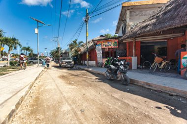 Tulum, Meksika 20 Ağustos 2025: İnsanlar Tulum, Meksika 'da kaldırımda yürüyorlar, güneşli bir günde dükkanları ve park edilmiş araçları var.