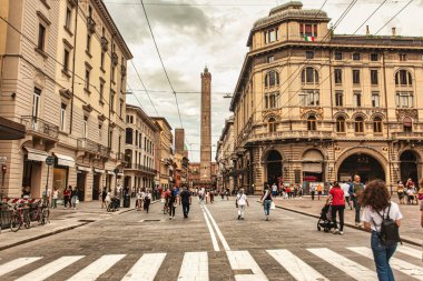 Bolonya, İtalya 19 Ağustos 2025: Rizzoli üzerinden dolaşırken, insanlar uzaktan yükselen ikonik asinelli kulesiyle Bolonya 'nın kentsel manzarasının tadını çıkarıyorlar.