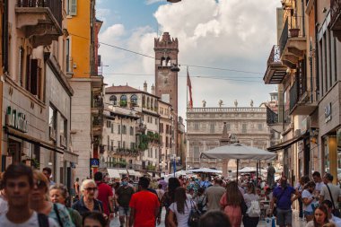 Verona, İtalya 20 Ağustos 2025: Torre dei lamberti ve palazzo maffei arka planda, verona, İtalya 'da turistler Piazza delle erbe' de yürüyorlar.
