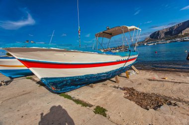 Mondello, İtalya, 20 Ağustos 2025: Geleneksel balıkçı teknesi Mondello 'nun kumlu sahilinde duruyor, Sicilya' da, arkasında Monte Pellegrino var.