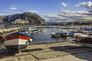 Mondello, İtalya 20 Ağustos 2025: Mondello 'daki pitoresk liman, renkli balıkçı tekneleri, Monte pellegrino muhteşem bir fon sağlıyor.