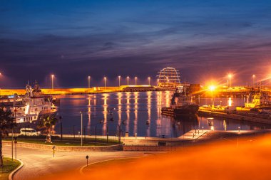 Civitavecchia, İtalya, 20 Ağustos 2025: Civitavecchia, İtalya 'da sakin bir akşam manzarası, aydınlatılmış gemiler ve su üzerindeki yansımalar