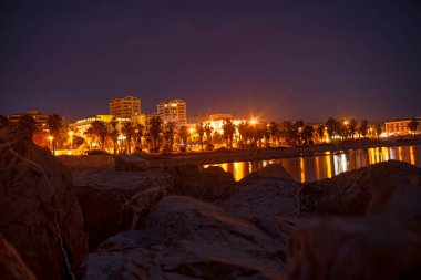 Civitavecchia, İtalya 20 Ağustos 2025: Civitavecchia, İtalya 'nın aydınlık şehir manzarası, geceleyin sakin Tyrhenian denizini yansıtıyor.