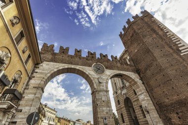 Verona, İtalya 20 Ağustos 2025: İtalya Verona, İtalya 'da saat ve kuleye sahip Porta Nuova şehir kapısı ve duvarlarının alçak açılı görüntüsü