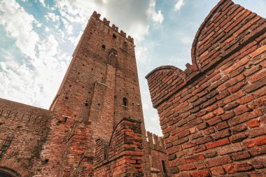 Verona, İtalya 20 Ağustos 2025: İtalya, Verona 'da Castelvecchio' nun ortaçağ mimarisi ikonik tuğla kuleyi ve bulutlu gökyüzüne karşı köprüyü gösteriyor.