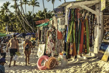 Dominik Cumhuriyeti, Dominik Cumhuriyeti 20 Ağustos 2025: Dominik Cumhuriyeti 'nin sahil bölgesinde turistlerle birlikte bir hediyelik eşya dükkanında asılı renkli kıyafetler