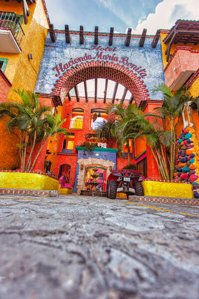 Playa del carmen, Мексика 20 августа 2025 года: вид с низкого угла на красочный вход отеля hacienda maria bonita, с пальмами и телевизором в playa del carmen, Мексика