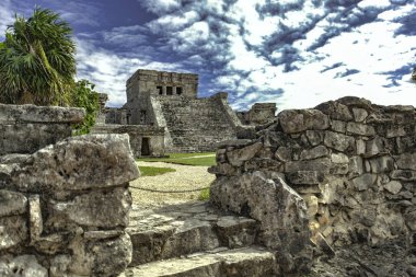 Quintana Roo, Meksika 'daki Tulum arkeoloji sahasında bulunan Maya mimarisinin taş kalıntıları bulutlu bir gökyüzüne karşı bir piramit tapınağı barındırıyor.