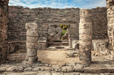 Taş sütunlar ve duvarlar Tulum, Meksika 'daki Mayalı bir medeniyetin kalıntıları gibi duruyor. Eski mimari ve tarihsel önemi gözler önüne seriyor.