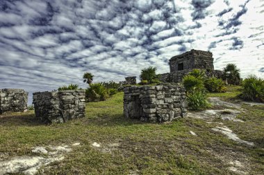 Antik Maya kalıntıları, Tulum, Meksika 'daki Karayip Denizi' ne bakan çimenli bir uçurumun üzerinde, dinamik bulutlu bir gökyüzünün altında duruyor.