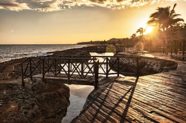 Tahta köprü ve deniz yolu Puerto aventuras, Riviera Maya, Meksika 'da altın gün batımını yansıtıyor.