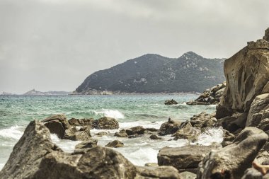 Turkuaz dalgaların arka planda Monte Turnu ile kayalara sıçrayan görüntüsü sardunya kıyılarının vahşi güzelliğini gözler önüne seriyor.