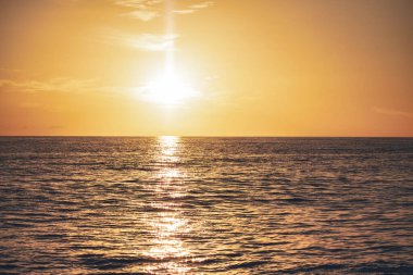 Batan güneş Dominicus 'un sakin okyanus suları boyunca ılık bir altın parıltı yayar, sakin ve nefes kesici bir sahne yaratır.