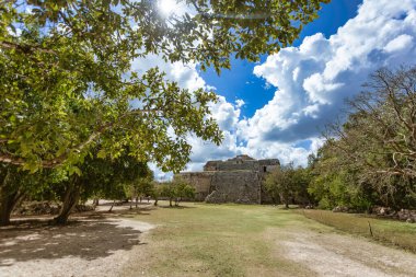 Güneş ışığı, Chichen Itza 'daki gözlemevini aydınlatıyor. Tüylü bulutlu, parlak mavi gökyüzüne karşı Maya mimarisi sergiliyor.
