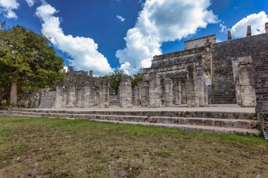 Chichen Itza 'daki savaşçıların görkemli tapınağında canlı bir gökyüzünün altında taş oymalar ve yüksek sütunlar sergileniyor.