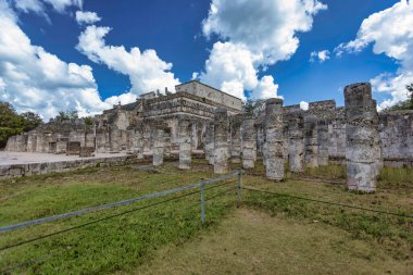 Yucatan, Meksika 'daki Chichen itza şehrindeki binlerce sütunluk heybetli harabeler bulutlu bir gökyüzünün altındaki antik bir tapınağı destekliyor.