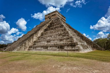 Chichen itza arkeolojik alanındaki etkileyici kukulkan piramidi tüylü beyaz bulutlarla kaplı canlı mavi gökyüzüne karşı dimdik ayakta duruyor.