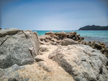 Cala Sinzias sahilindeki granit kayalıkların nefes kesici manzarası turkuvaz suları ve sardunya, İtalya 'da açık mavi bir gökyüzü.