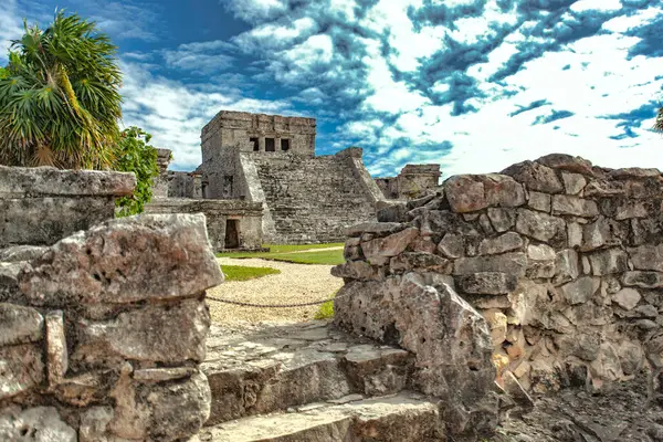 Quintana Roo, Meksika 'daki Tulum arkeoloji sahasında bulunan Maya mimarisinin taş kalıntıları bulutlu bir gökyüzüne karşı bir piramit tapınağı barındırıyor.