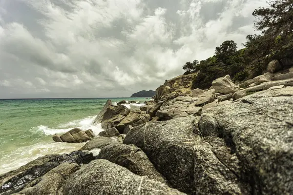 Turkuaz dalgalar Monte Turnu, İtalya 'da bulutlu bir gökyüzünün altında kayalık bir kıyı şeridine çarpıp dramatik ve pitoresk bir manzara yaratıyor.