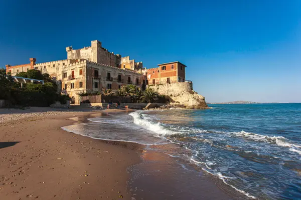 Yumuşak dalgalar sahilin kumlu sahillerine vuruyor Sicilya 'da tarihi şahin şatosu berrak mavi gökyüzünün altında görkemli bir şekilde duruyor.