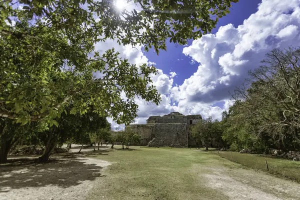 Güneş ışığı, Chichen Itza 'daki gözlemevini aydınlatıyor. Tüylü bulutlu, parlak mavi gökyüzüne karşı Maya mimarisi sergiliyor.
