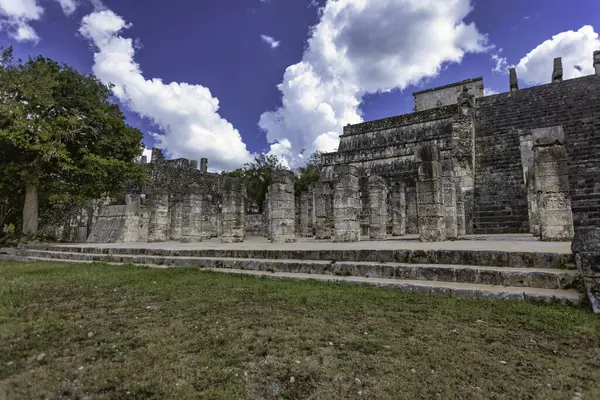 Chichen Itza 'daki savaşçıların görkemli tapınağında canlı bir gökyüzünün altında taş oymalar ve yüksek sütunlar sergileniyor.