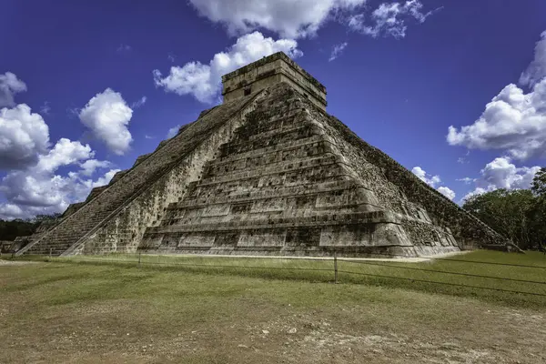 Chichen itza arkeolojik alanındaki etkileyici kukulkan piramidi tüylü beyaz bulutlarla kaplı canlı mavi gökyüzüne karşı dimdik ayakta duruyor.