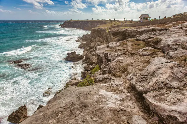 Okyanus dalgaları Punta sur, Isla Mujeres, Meksika 'daki engebeli kayalık sahil şeridine çarpıyor güneşli bir gökyüzünün altında çarpıcı bir deniz manzarası yaratıyor.