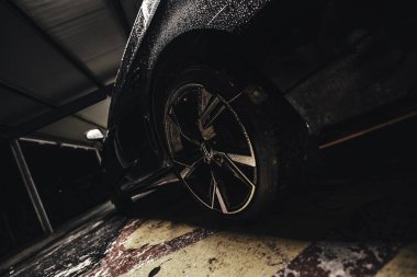 Rome, italy 30 september 2025: wet audi wheel and alloy tire in dark gritty parking garage, rain droplets on sleek body and reflective rim, low-angle detail.