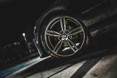 Rome, italy 30 september 2025: bmw wet alloy wheel and tire glistening with rain drops at night, reflecting city lights and asphalt for a premium automotive close-up
