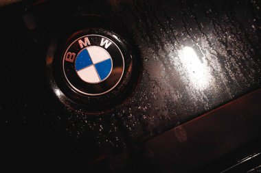 Rome, italy 30 september 2025: bmw emblem glistening with rain droplets at night, sleek chrome and blue-white badge reflecting luxury automotive engineering