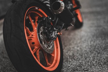 Padova, italy 1 october 2025: close-up of ktm rear motorcycle wheel with orange rim, tire, brake disc and exhaust on asphalt for urban sportbike action