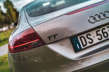 Rome, italy 30 september 2025: silver audi tt rear view showcasing glossy taillight, emblem and european license plate against blurred urban background