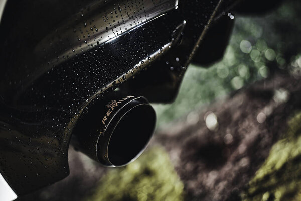 Rome, italy 30 september 2025: sporty black remus exhaust with water droplets on wet bumper, close-up capturing glossy tuned performance detail and reflection